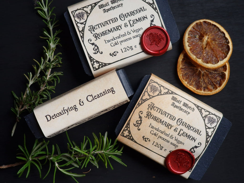 Two soap bars with labels and dried oranges on a dark background