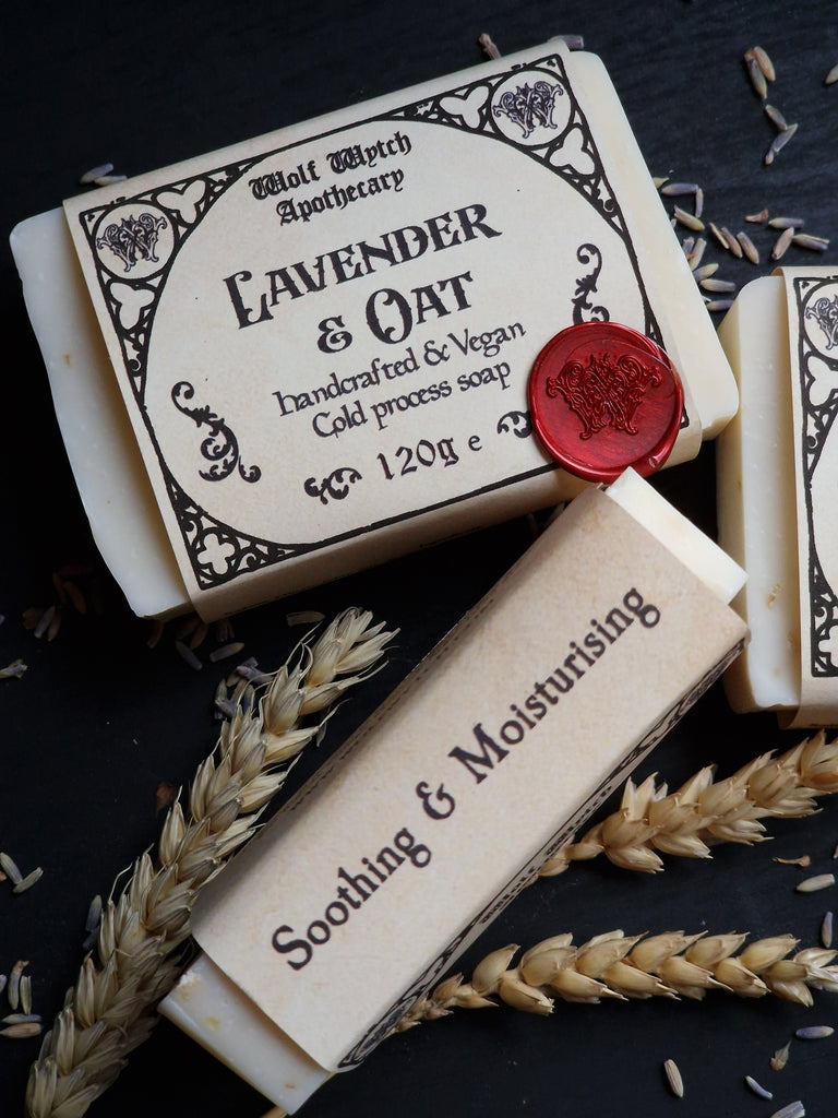 Two bars of soap with decorative labels and a red wax seal on a dark surface with wheat stalks.