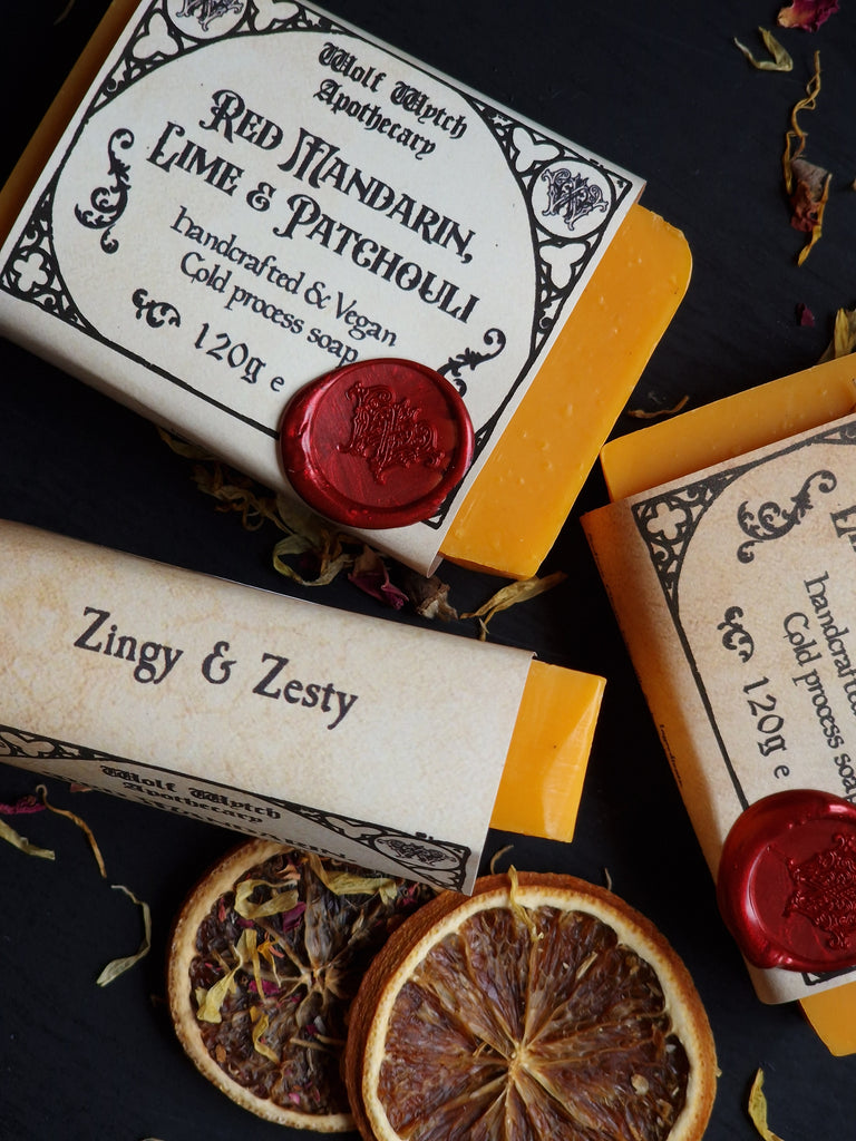 Three bars of soap with decorative packaging and labels on a dark surface.